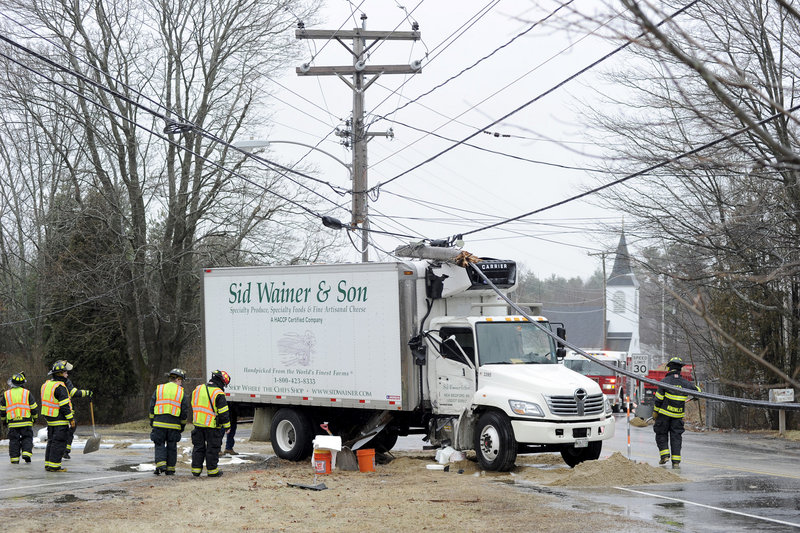 Falmouth firefighters spread sand in an attempt to contain a fuel spill after a box truck skidded off Route 9 in Falmouth and slammed into a utility pole, cutting the pole in half.