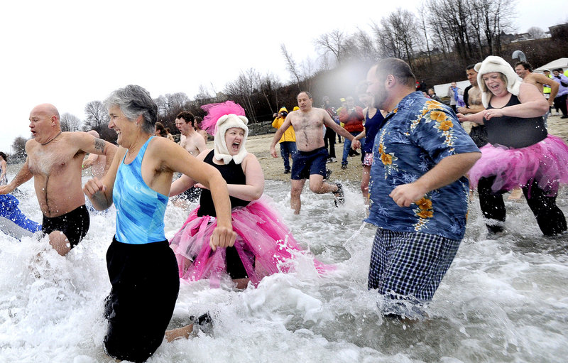 Janine Palmer of Norwell, Mass., and Beth Dimond of Winthrop, both dressed in pink, react to the cold water as they were among over 100 bathers to participate in the annual Polar Bear Plunge at East End Beach in Portland on Saturday.