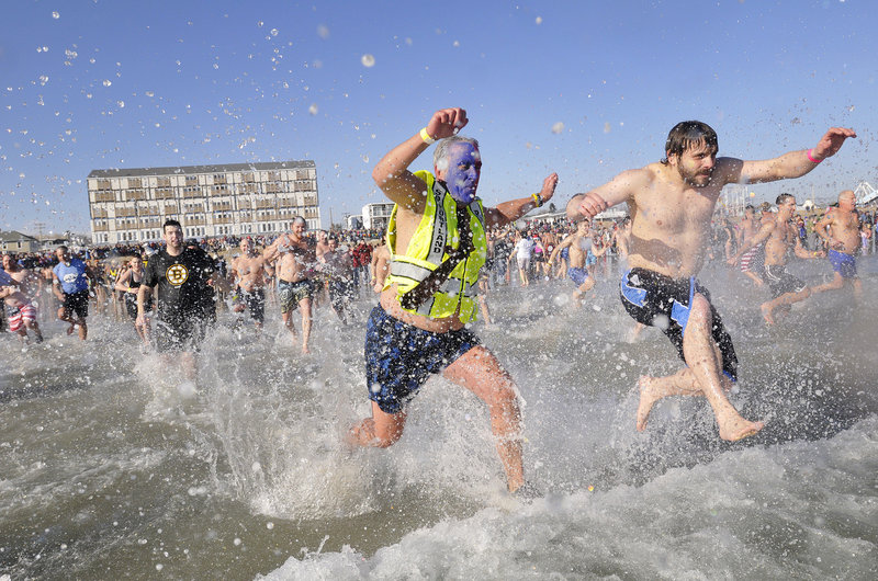 Peter MacVane, center, a founder of the fundraiser, leads the plunge in the 24th annual Lobster Dip in Old Orchard Beach on Sunday. The temperatures – 43 degrees for the air and 45 for the water – made it a bit easier than past New Year’s Day dips.