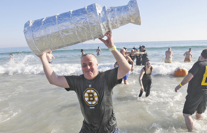 Don Hill of Team Brunswick hoists a fake Stanley Cup after his dip at Old Orchard Beach.