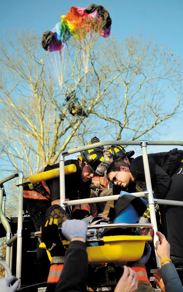 Firefighters and police lower John Beganny to the ground Sunday after rescuing him from a tree in Litchfield.