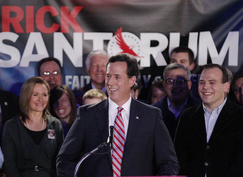 Former Pennsylvania Sen. Rick Santorum, joined by his wife Karen, left, addresses supporters after the Republican presidential caucus on Tuesday in Johnston, Iowa. His campaign is racing to raise funds and to organize in primary states.