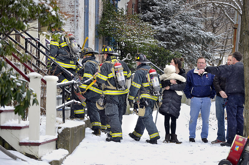 Portland firefighters head into 190 Danforth St. on Friday morning to put out a fire in a second-floor apartment, as Deputy Chief David Pendleton, right, talks with tenants. No one was injured but there was heavy smoke in the building.