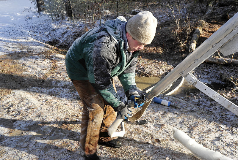 Ben Susla, who constructed the five snow guns owned by Pineland Farms, attaches an air hose to one of the guns in preparation for more snowmaking.