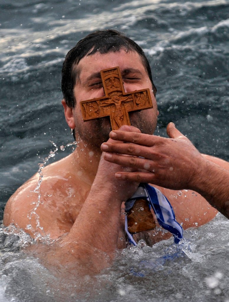 Panagiotis Mantziaris kisses the wooden cross after being the first to retrieve it Friday during an Epiphany ceremony to bless the water in Greece’s northern port city of Thessaloniki.