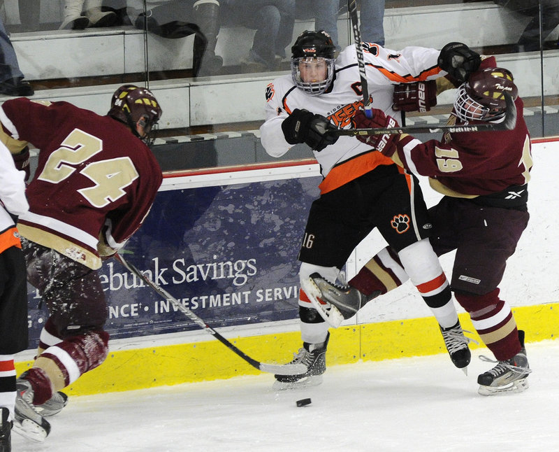 Tyler Danley, left, of Thornton Academy takes control of the puck as his teammate, Robbie Downing, ties up Taylor Reuillard of Biddeford during their game at the Biddeford Ice Arena.