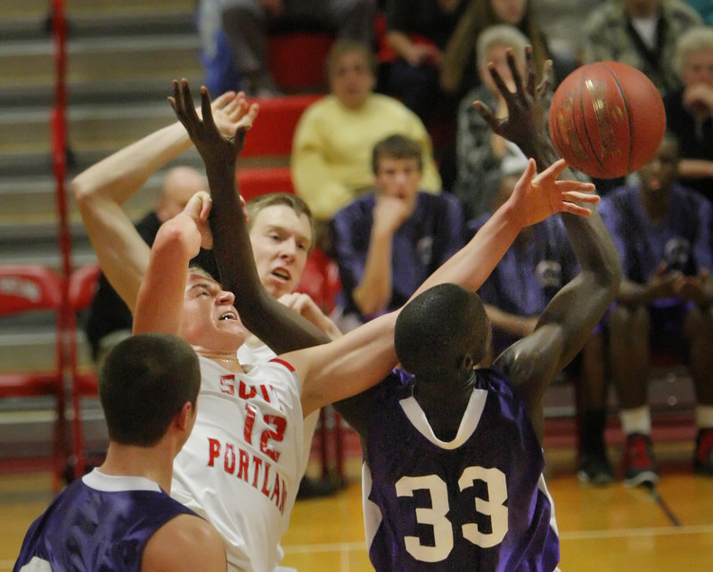 Ben Burkey of South Portland, left, and Labson Abwoch of Deering contend for a rebound during their physical game Friday night. Unbeaten Deering earned a 40-29 victory.