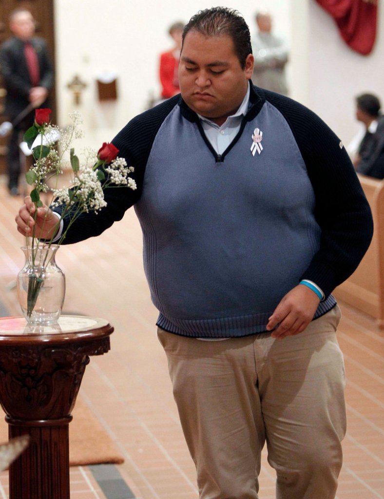 Daniel Hernandez, a former intern for Rep. Gabrielle Giffords who was praised for coming to her aid after a Jan. 8, 2011, shooting rampage, leaves one of six roses for the six shooting victims at a remembrance service Sunday in Tucson, Ariz.