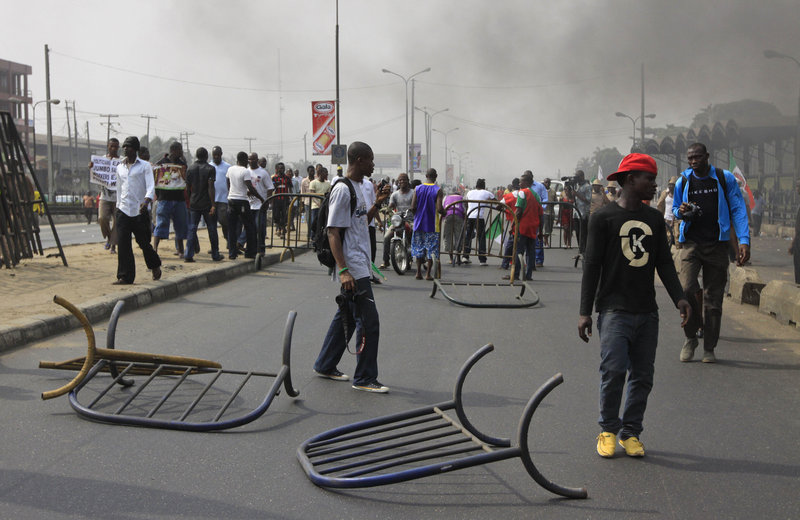People walk past barricades mounted in Lagos, Nigeria, on Monday. A national strike paralyzed much of the nation.