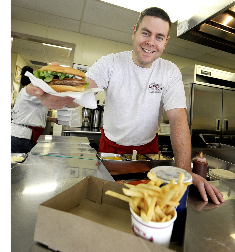 Robert Roberge, grandson of founder Renald “Ray” Camire, serves up a Rapid Ray’s cheeseburger.