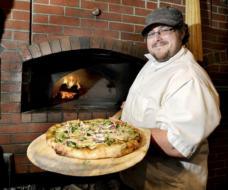 Sous chef Jeffrey Smith removes a Bolto pizza, which features pesto sauce, roasted chicken, broccoli, red onions and Fontina cheese, from the wood-fired oven at Ricetta’s in Falmouth.