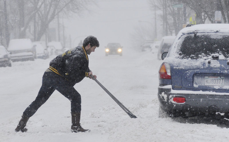 Peter Casasa-Blouin of Portland clears snow from around his car on Congress Street in Portland during Thursday’s snowfall.