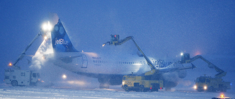 A JetBlue plane is de-iced before takeoff Thursday at the Portland International Jetport. Precipitation from the storm changed over from snow to freezing rain along the coast.