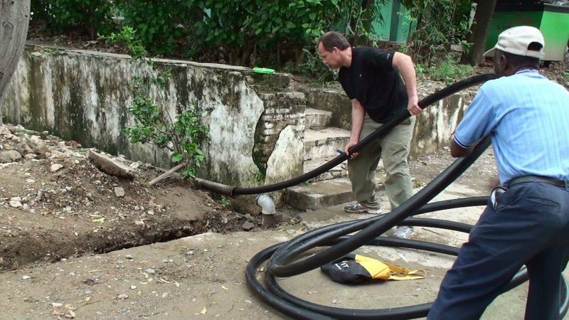 Hugh Tozer, left, a wastewater engineer from South Portland and volunteer chair of Konbit Sante’s infrastructure improvement team, works with Haitian colleague Bon Jacques to install piping for a second well at Justinian Hospital in Cap-Haitien during one of the group’s trips there.