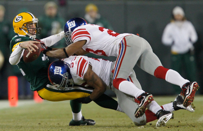 Aaron Rodgers gets sacked by Michael Boley, bottom, and Corey Webster in Sunday’s playoff game at Green Bay, Wis. Rodgers was sacked three other times as the Giants advanced to the NFC championship game with a 37-20 victory.