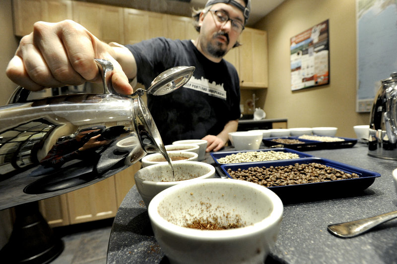 Coffee By Design head roaster Dylan Hardman adds water to the coffee for steeping before a tasting.