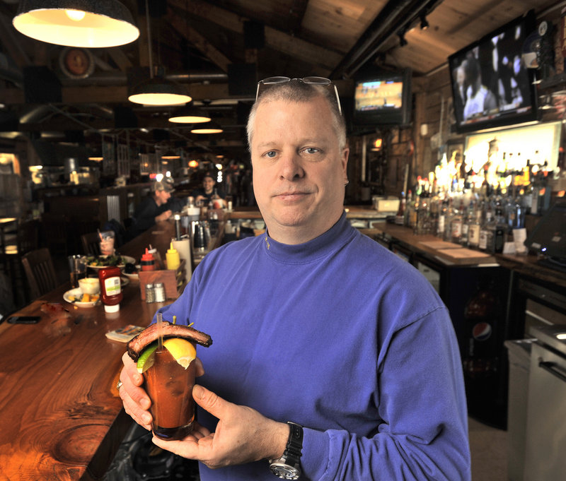 Bartender Evan Horton behind the bar at Buck’s Naked BBQ in Freeport with a featured drink, the Bloody Buck.