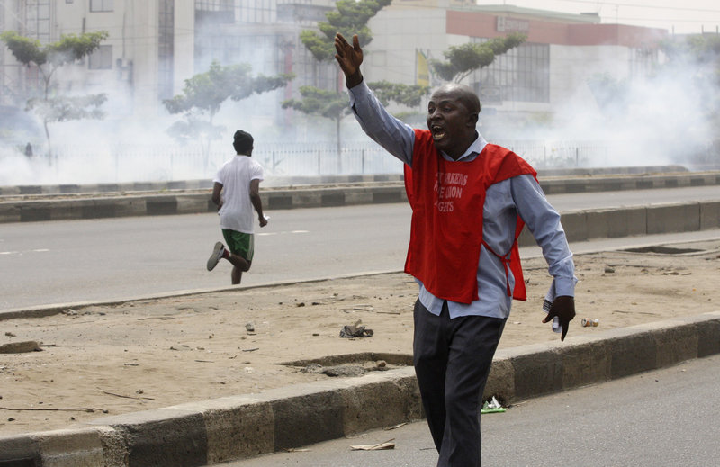Protesters run from tear gas fired by police during a demonstration against spiraling fuel prices in Lagos, Nigeria, on Monday. For the first time since protests erupted over fuel prices, soldiers barricaded key roads Monday in the nation’s two biggest cities.