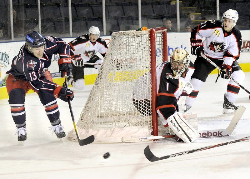 Cam Atkinson of the Falcons makes a pass as Pirates goalie Justin Pogge watches the puck Friday night. Atkinson scored his 22nd goal of the season, but Portland earned a 5-3 win.