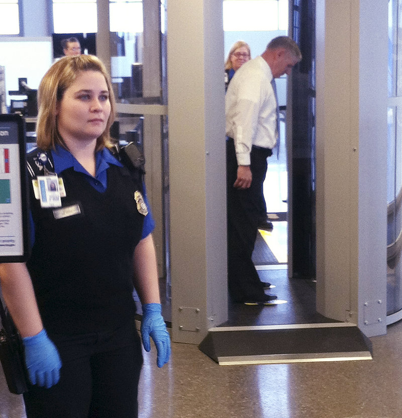 TSA screener Kayla Kelly stands near the new scanners, while behind her TSA screener Gordon Field is scanned.