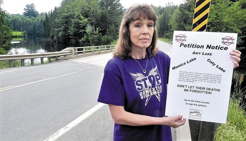Sandra Mitchell holds a petition on the Higgins Stream Bridge in Harmony. The bridge and another nearby would be renamed to bring awareness to domestic violence issues.