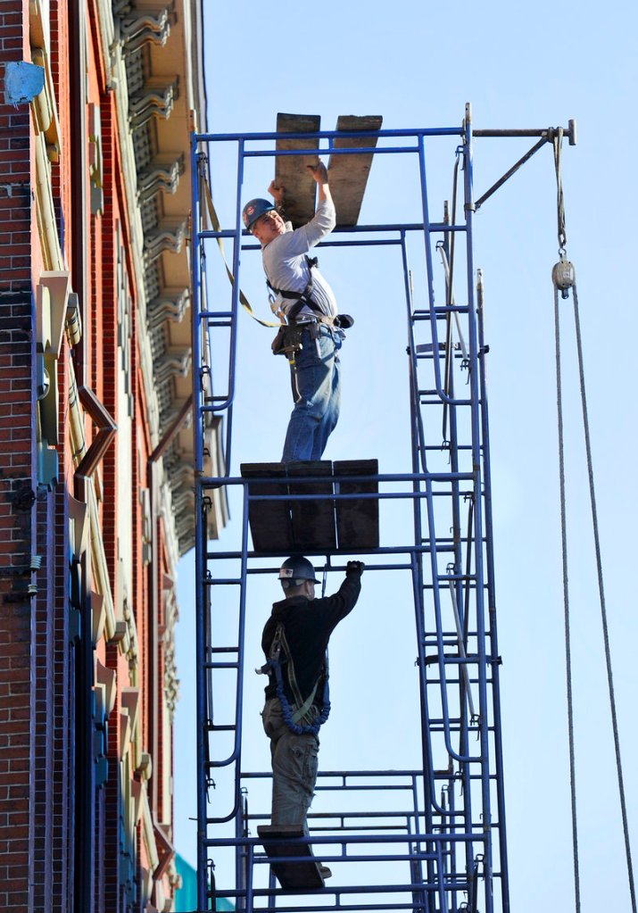 Lee McLaskey, top, and John Maxwell, workers from Portland-based Masonry Preservation Associates, erect scaffolding Tuesday outside the Woodman Building at Pearl and Middle streets in Portland. The historic structure, built in 1867, needs repairs to its gutters.