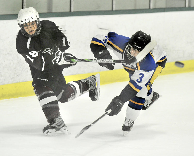 Chelsey Andrews of Greely clears the puck from her zone while pressured by Falmouth’s Abby Payson.