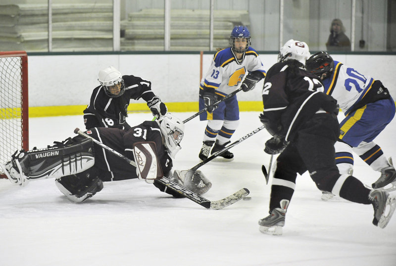 Greely goalie Emma Seymour dives to cover a loose puck as Falmouth’s Maddy McDonnell moves in on the play Monday night at Family Ice Center in Falmouth. Falmouth earned the win with three third-period goals.