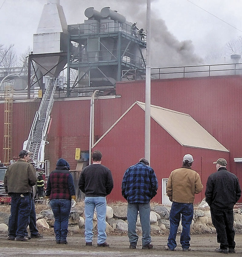 Workers watch as smoke billows from the Geneva Wood Fuels plant on Thursday morning. The fire started on the third floor about 8 a.m.
