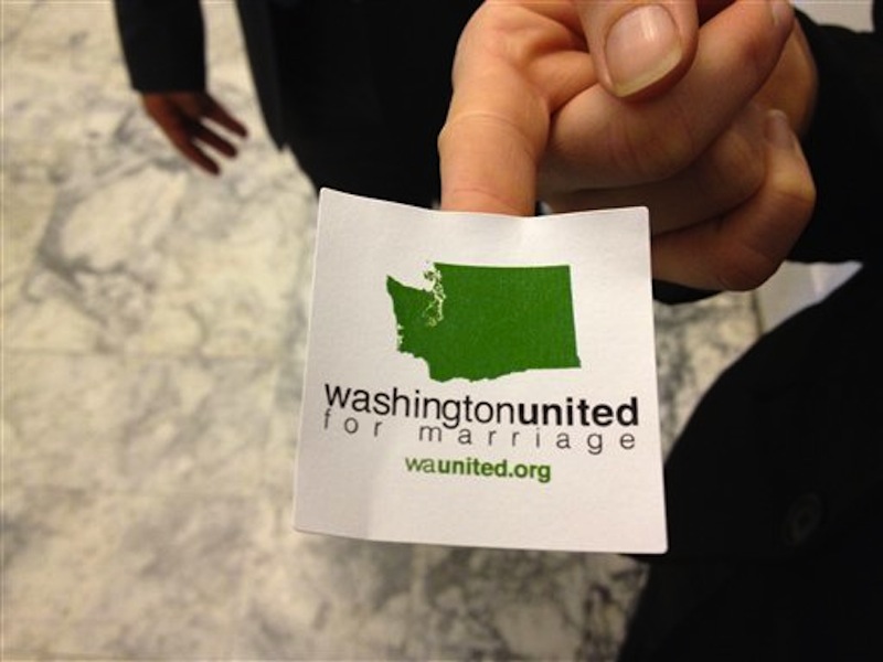A supporter of gay marriage hands out stickers outside an overflow room for a Senate committee hearing on proposed legislation that would legalize same-sex marriage, Monday, Jan. 2 at the Capitol in Olympia, Wash. (AP Photo/Ted S. Warren)