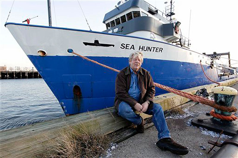 Greg Brooks, co-manager of Sub Sea Research, poses alongside the salvage ship Sea Hunter in Boston Harbor Wednesday, Feb. 1. Brooks says he will use the Sea Hunter to salvage the cargo of 71 tons of platinum now worth about $3 billion from the British merchant ship Port Nicholson which was sunk by a German U-boat in 1942. (AP Photo/Winslow Townson)