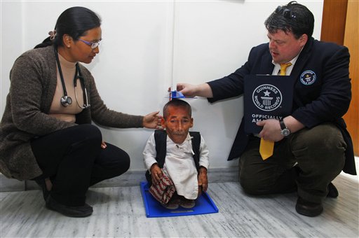 Editor in Chief of Guinness World Records Craig Glanday, right, and Dr. Kashila Pradhan, left, officially measure Nepal's Chandra Bahadur Dangi, 72, who says he's only 22 inches (56 centimeters) tall, at the CIWEC clinic in Katmandu, Nepal, Sunday, Feb. 26, 2012. (AP Photo/Niranjan Shrestha)