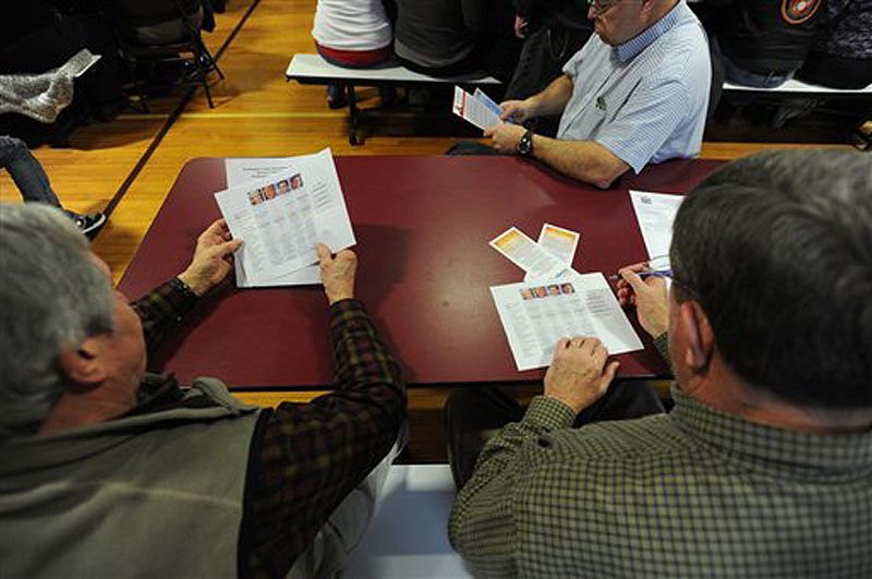 Republican voters Elton Anderson, left, of Milbridge and Gary Willey, right, review presidential comparison materials before the Washington County Republican Super Caucus on Saturday at Washington Academy in East Machias. More than 300 people cast ballots at the event.