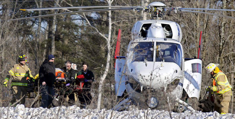 A patient from a motor vehicle accident that occurred Sunday on Route 202 in Winthrop is escorted to a helicopter for transport to a hospital.