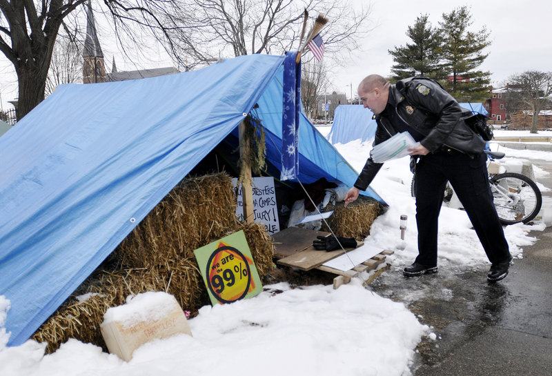 Sgt. Andy Hutchings drops off a notice to vacate at a tent in Lincoln Park in Portland on Thursday. The city is giving Occupy Maine protesters until Monday morning to move out.