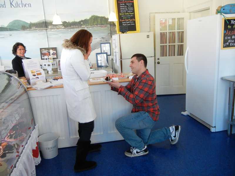 The would-be groom proposes to his beloved at Cranberry Island Kitchen in Portland, with the ring concealed in a whoopie pie and store co-owner Karen Haase looking on approvingly. Michael and Amber Snyder were married on Jan. 10.