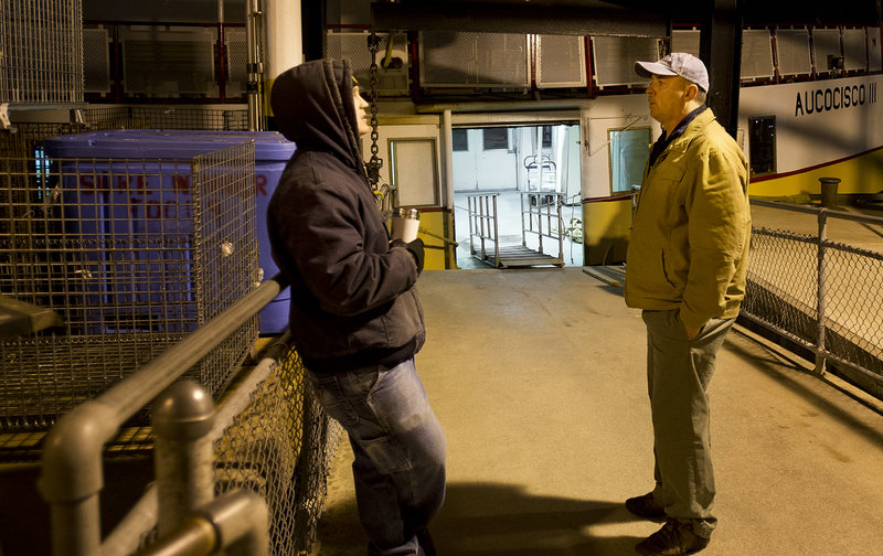 Gene Willard talks with deckhand Andy Gildart, left, at 4:56 a.m., before boarding the Aucocisco II for the morning run to the islands.