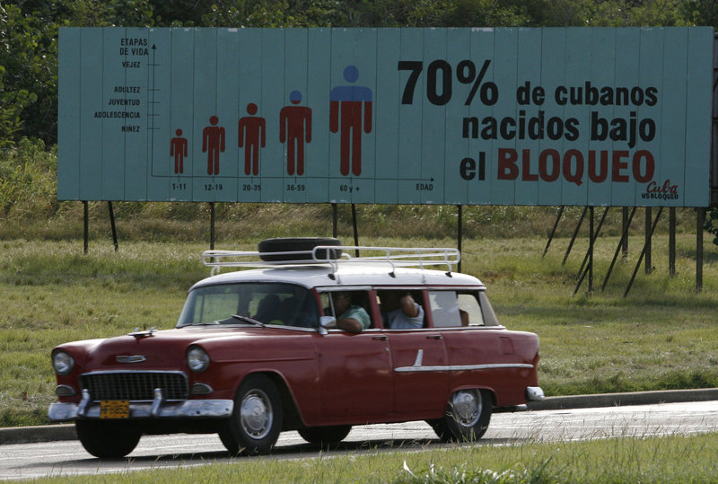 A motorist passes a billboard in Havana that reads: “70 percent of Cubans have been born under the embargo.” Fifty years of socialism have brought Cuba advancements in education and health care, but even authorities there admit their economic system must change.
