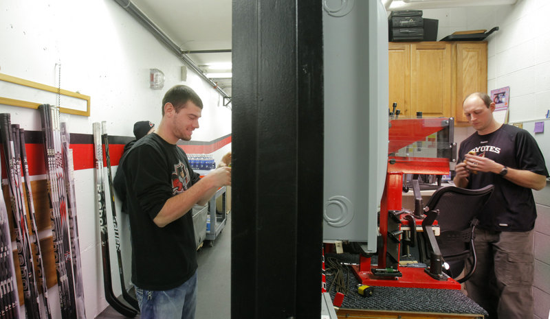 Justin Barto, assistant equipment manager, left, and John Krouse, equipment manager, prepare for a Portland Pirates road trip in crowded quarters at the civic center. Krouse’s small office also serves as a laundry room and repair shop.