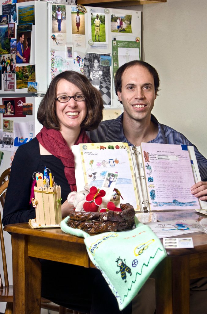 Sarah and Eric Fox-Linton show off photos, letters and gifts from the three children they are sponsoring through Compassion International at their home in Atchison, Kan.