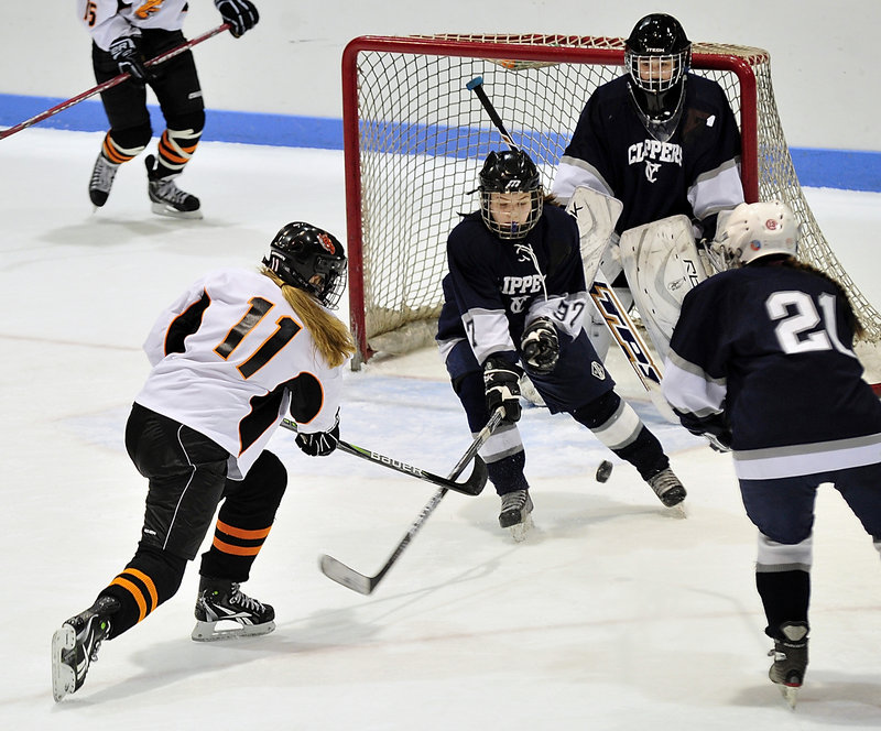 Gillian Ford of Brunswick attempts to slip the puck past defender Meredith McLoon and goalie Hannah Williams of Yarmouth-Freeport as Gage Thurston of Yarmouth-Freeport skates in. Brunswick won the East semifinal, 6-1.