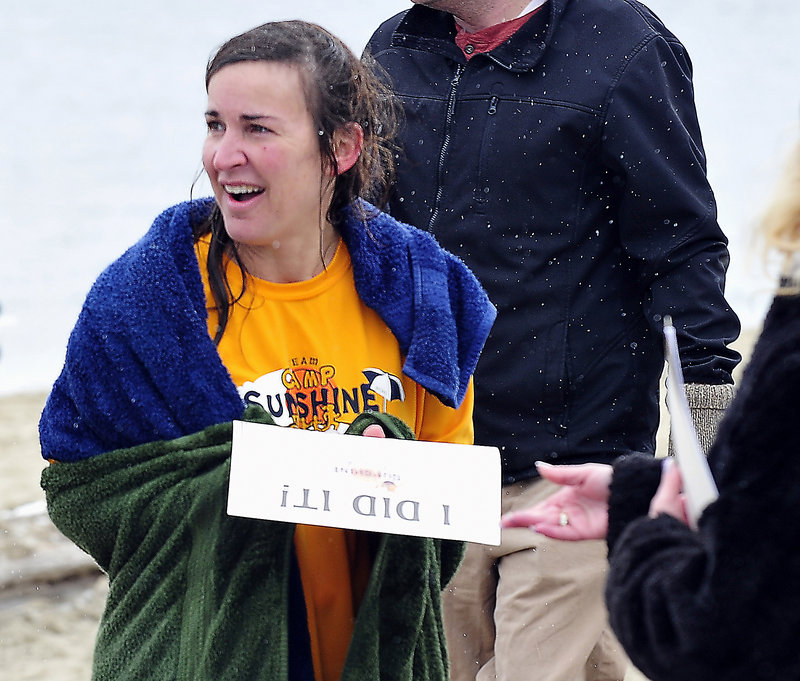 The snow is still falling as Cathy Jerome of Boston gets her “I Did It!” certificate after participating in the Camp Sunshine fundraising dip at East End Beach in Portland.