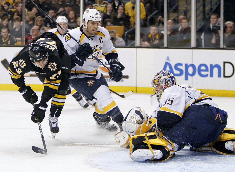 Chris Kelly of the Bruins loses his balance after taking a shot on Nashville goalie Pekka Rinne as the Predators’ Shea Weber defends Saturday in Boston. The Bruins broke a two-game home losing streak with a 4-3 shootout win.