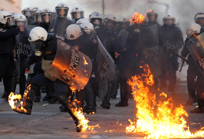A Greek riot police officer tries to extinguish flames from a gasoline bomb thrown by protesters outside parliament in Athens on Feb. 12. The Greek economy is in its fifth year of recession, and unemployment tops 20 percent.