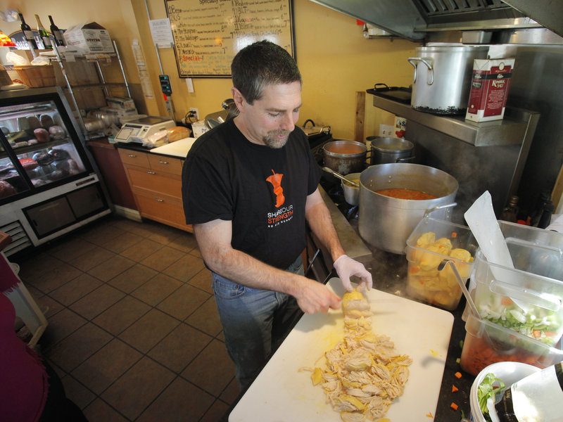 Pete Leavitt of Leavitt & Sons Deli in Falmouth shreds chicken for some of the 15 to 30 pies he sells daily.