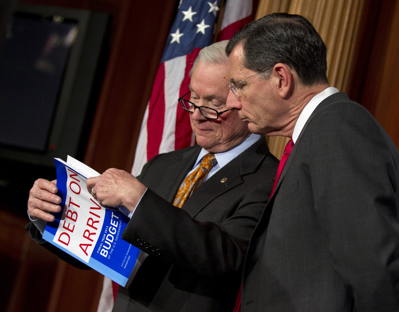 After attaching a “Debt on Arrival” label, Republican Sens. Jeff Sessions of Alabama, left, and John Barrasso of Wyoming look over President Obama’s fiscal 2013 budget Monday.
