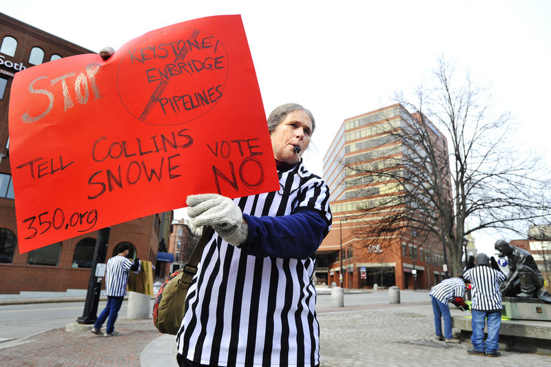 FUEL FOR PROTEST: Hilary Clark of York wears a referee’s shirt Tuesday at Middle and Temple streets in Portland, where protesters gathered to “blow the whistle” on members of Maine’s congressional delegation who have benefited from oil industry donations.