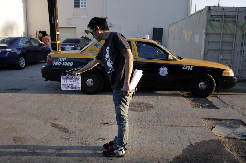 Crew member Arthur Hong holds a clapboard while filming holiday movie trailers at Maker Studios in Culver City, Calif. The $100 million investment by YouTube in 96 new channels starting in October has sparked a flurry of activity in Hollywood’s independent producer community.