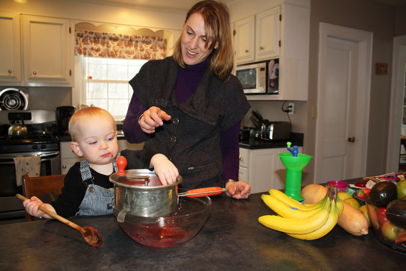 Christine Wirth and her 14-month-old son, Joseph, make applesauce using a metal food mill.