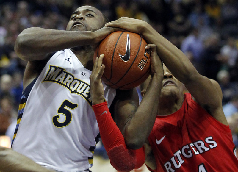 Junior Cadougan of Marquette battles for the ball with Myles Mack of Rutgers during Wednesday’s game in Milwaukee. Marquette won, 82-65.